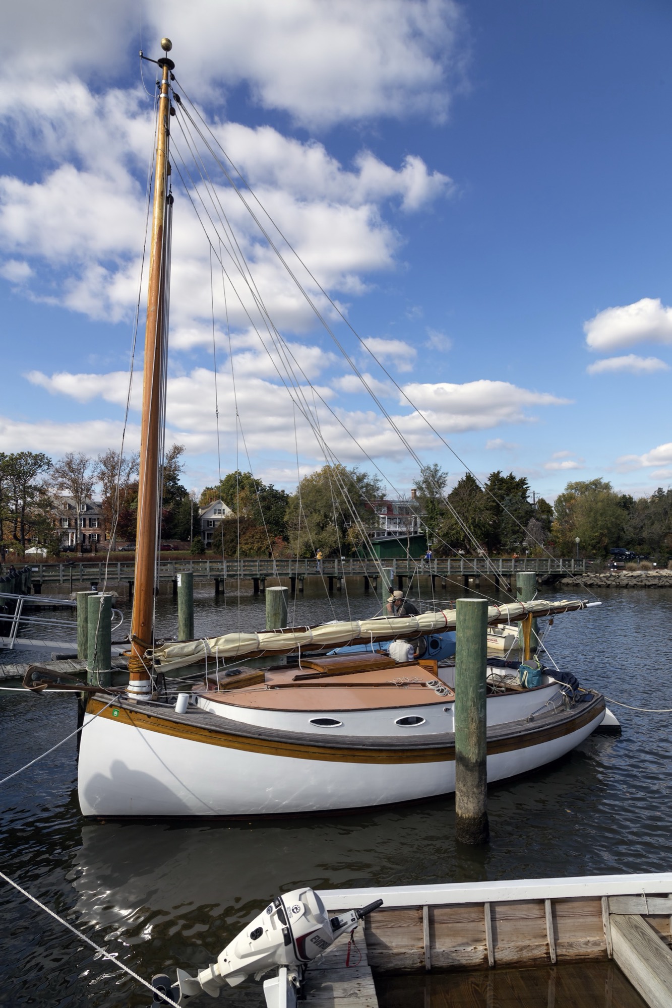 A wooden catboat tied up at the dock in Chestertown, Maryland, under a blue sky