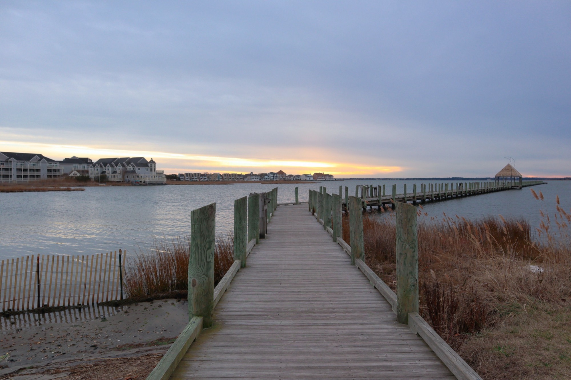 A wooden pier reaching into the bay behind Ocean City, Maryland, at sunset