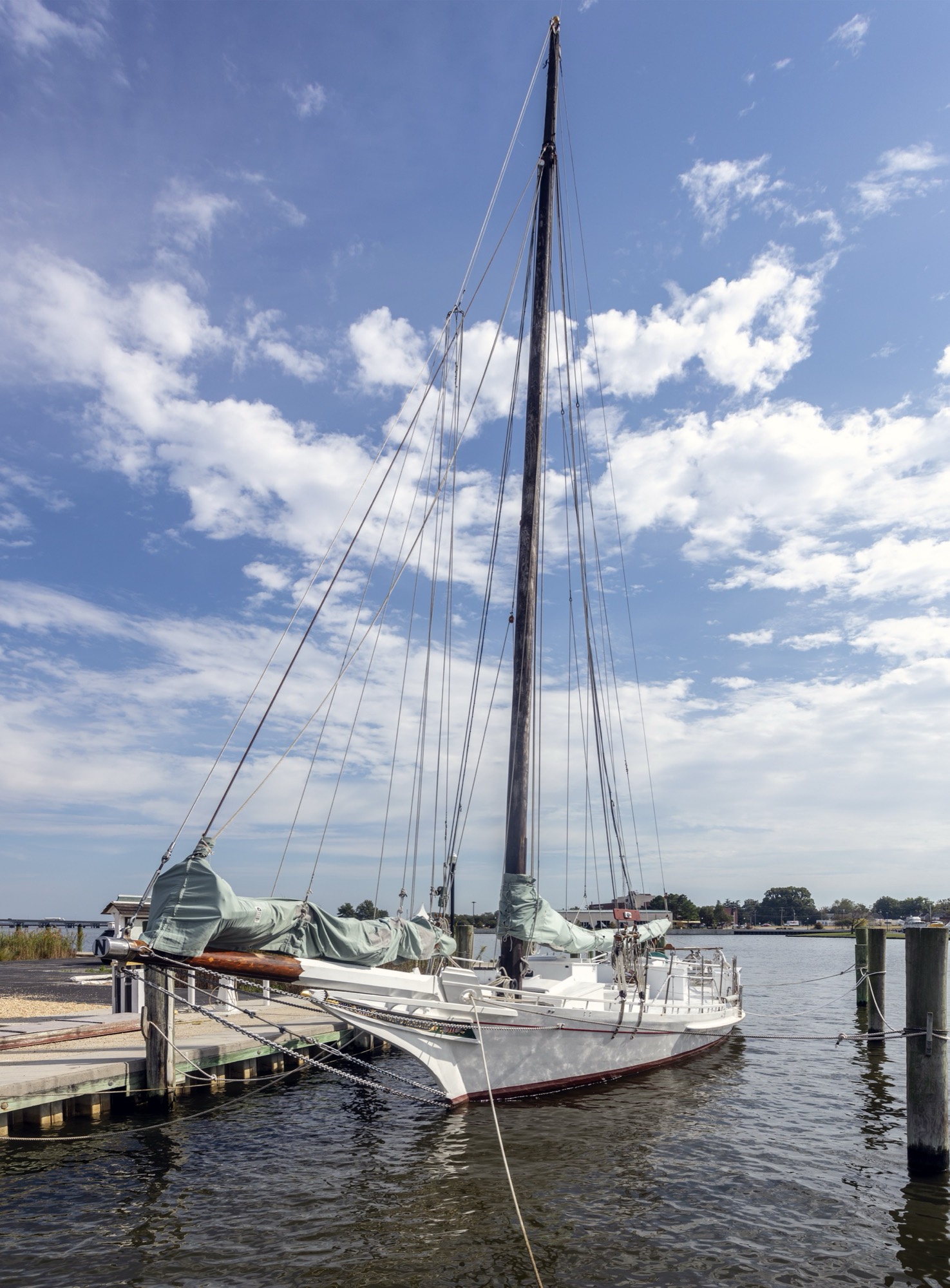 The skipjack Nathan of Dorchester tied up at Cambridge, Maryland, masts against the clouds