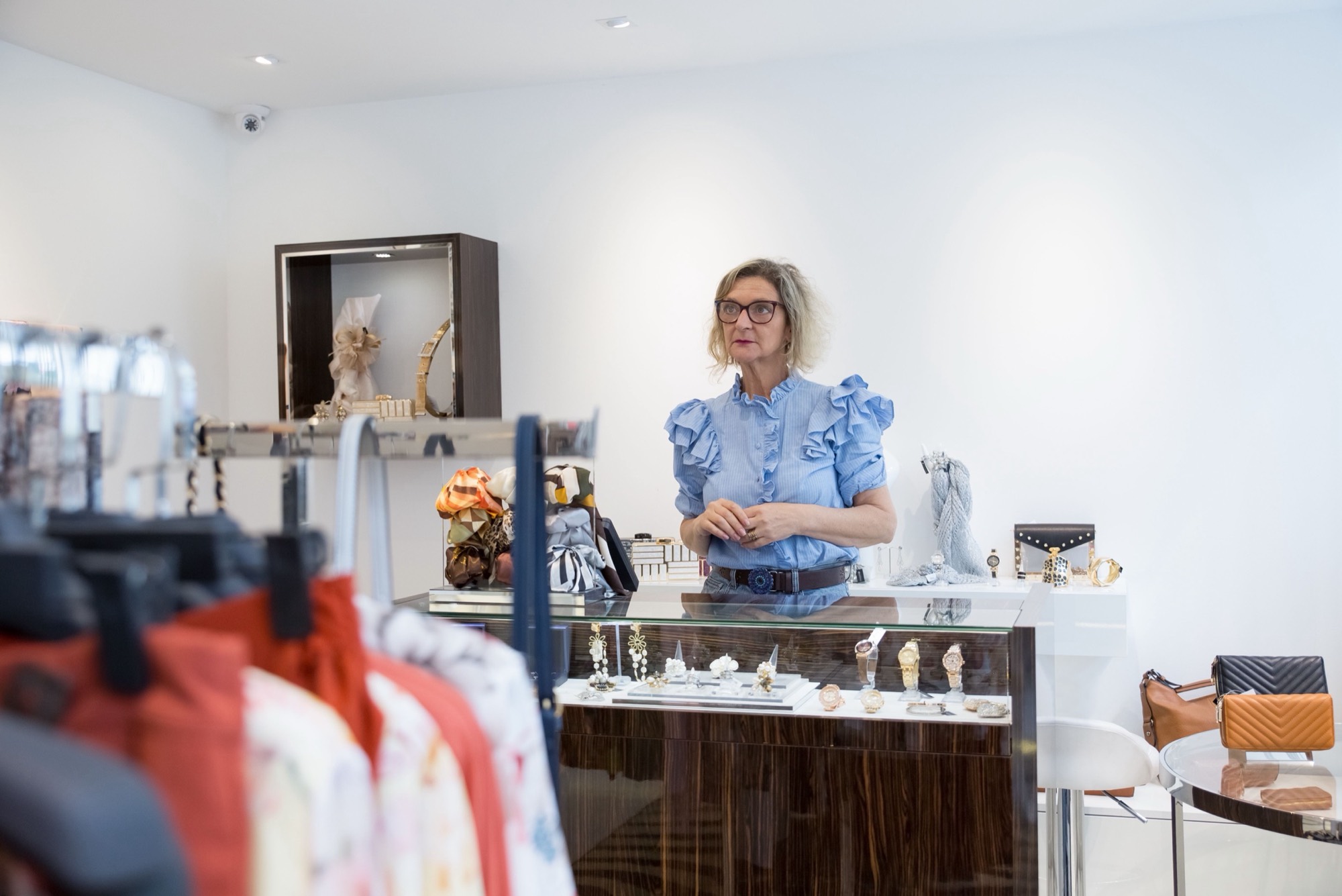 A boutique owner standing at the counter of her clothing shop