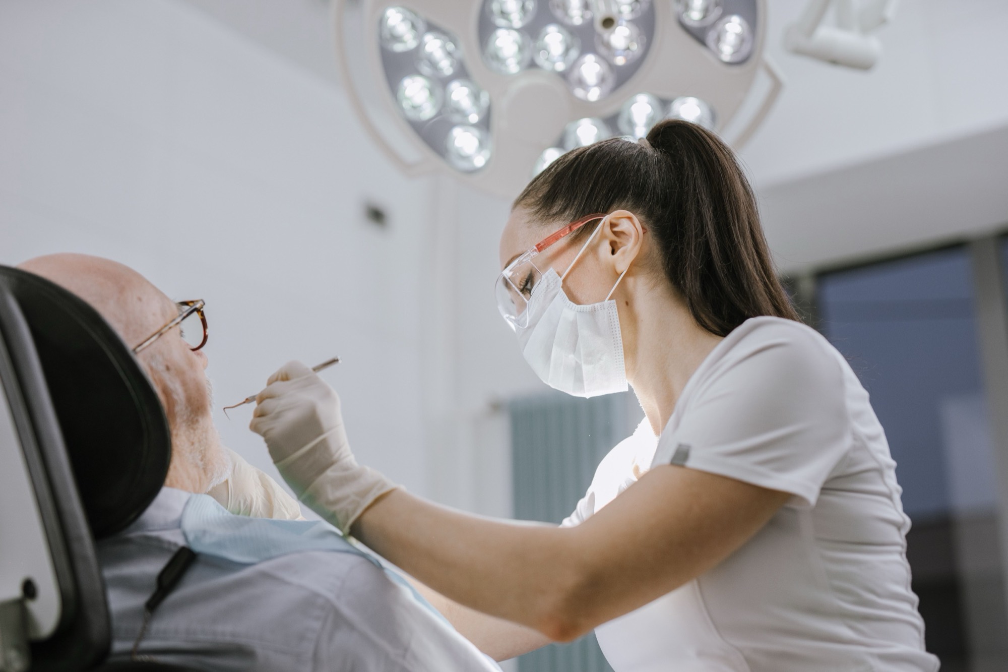 A dentist in a mask examining a patient in the chair