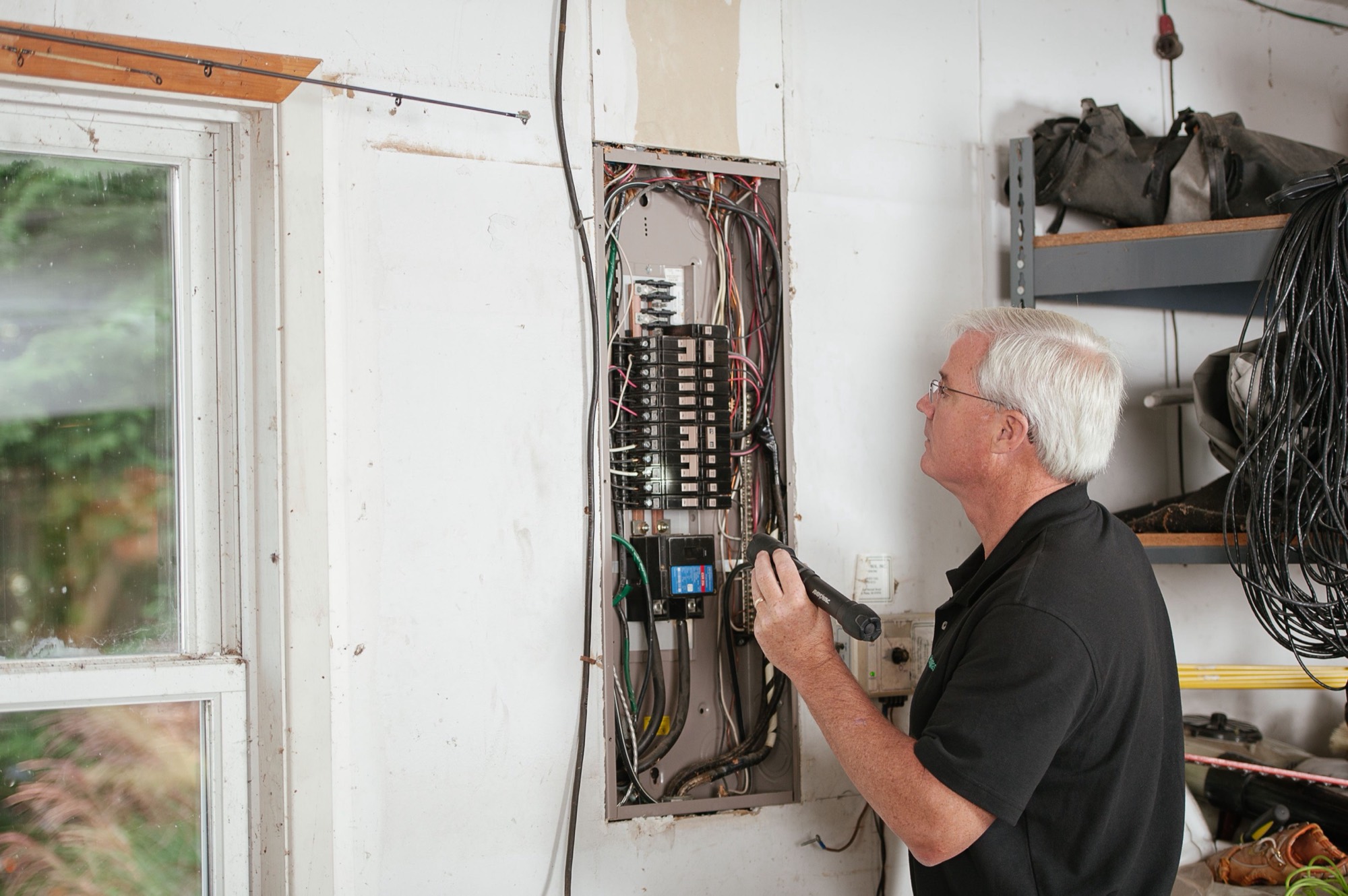 An electrician checking a home electrical panel in a workshop