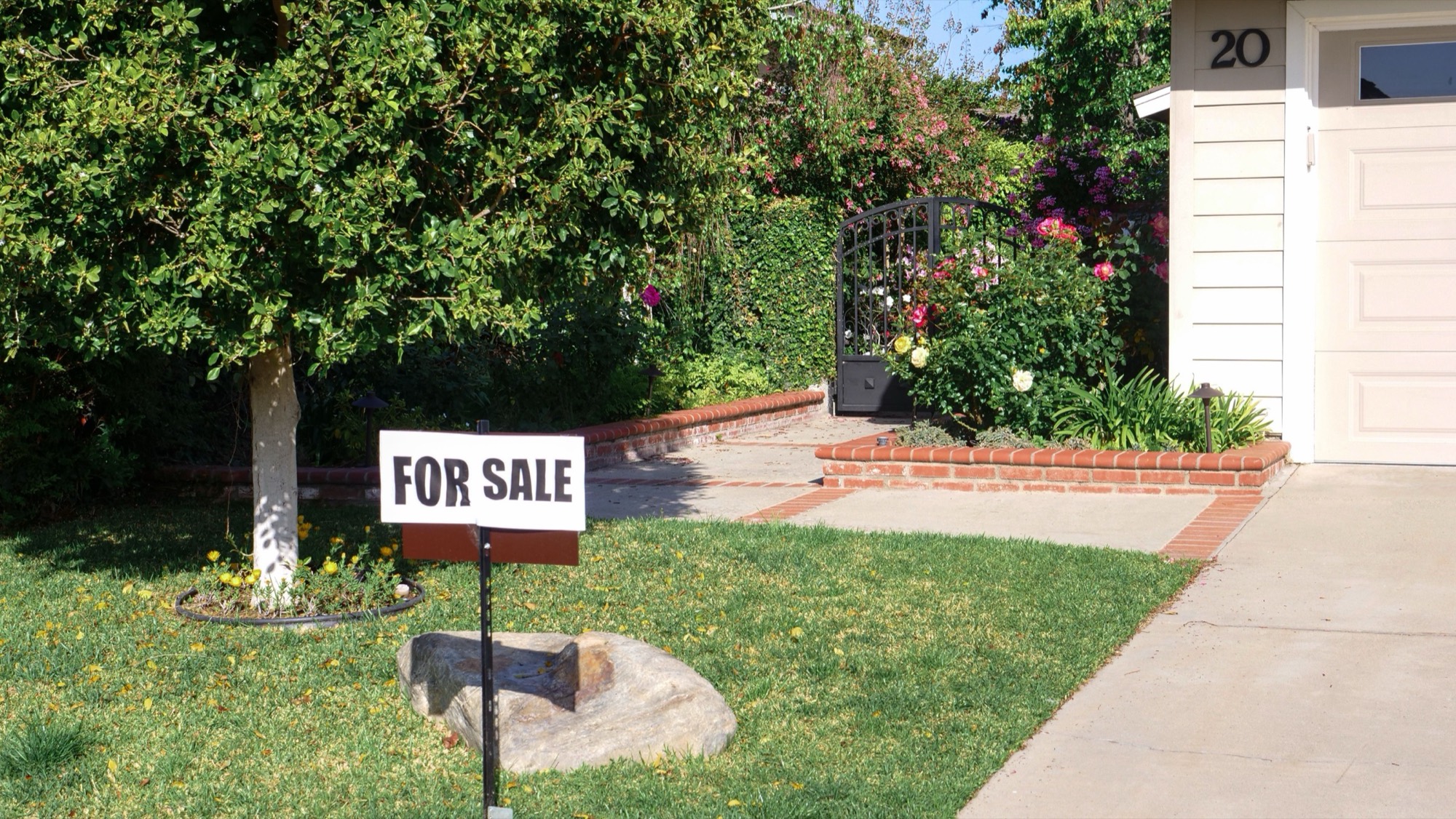 A for-sale sign on the front lawn of a house