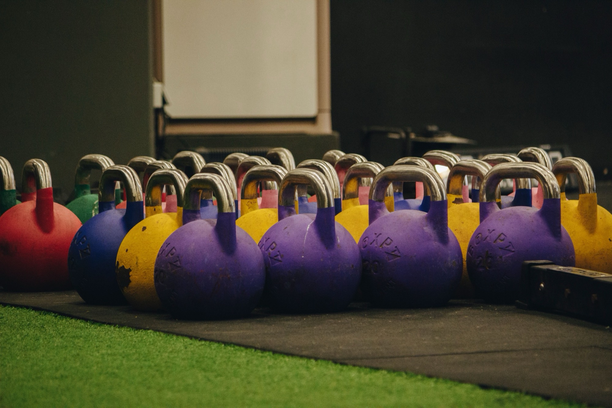 Rows of colourful kettlebells lined up on a gym floor