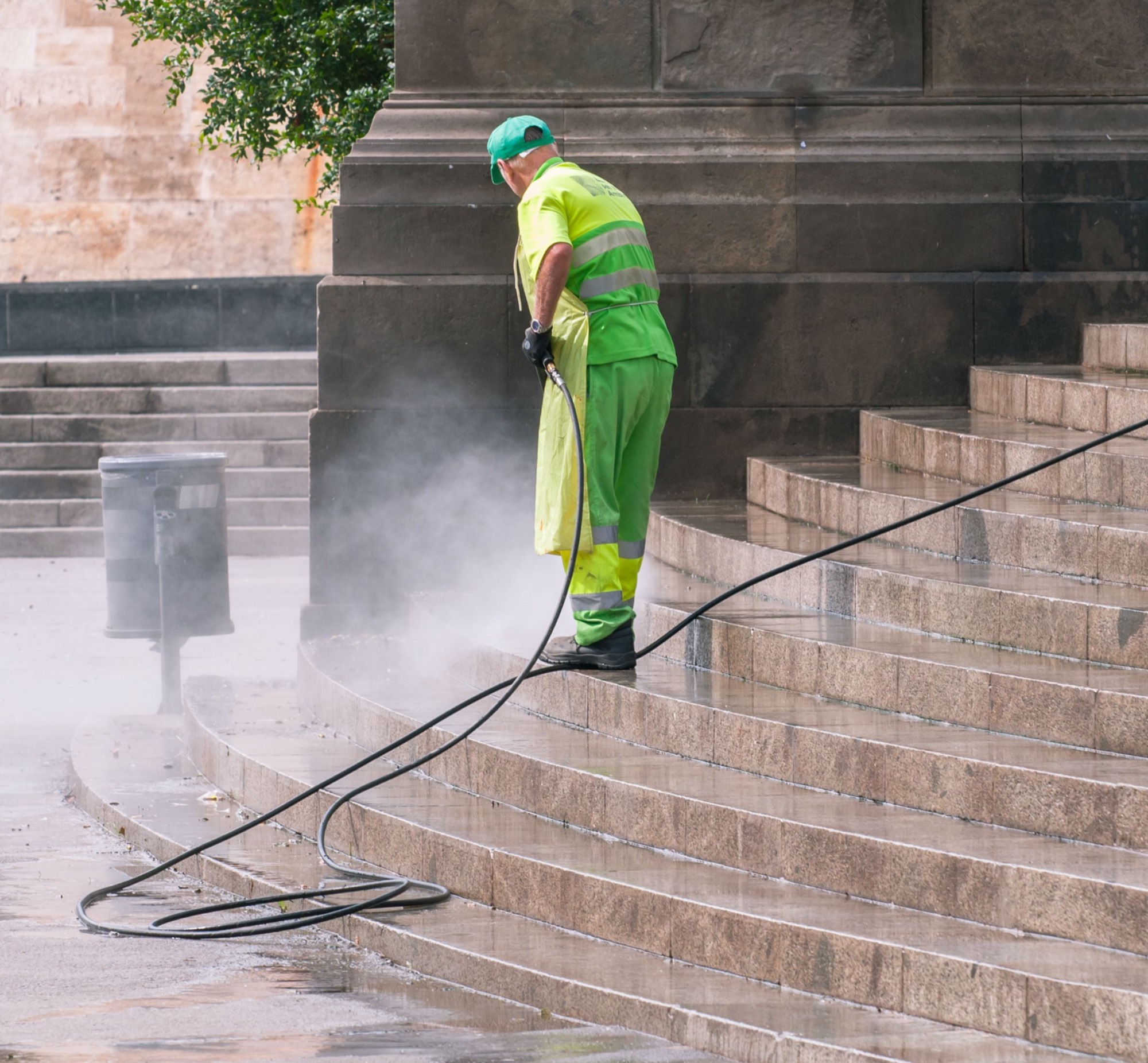 A worker pressure washing a flight of stone steps
