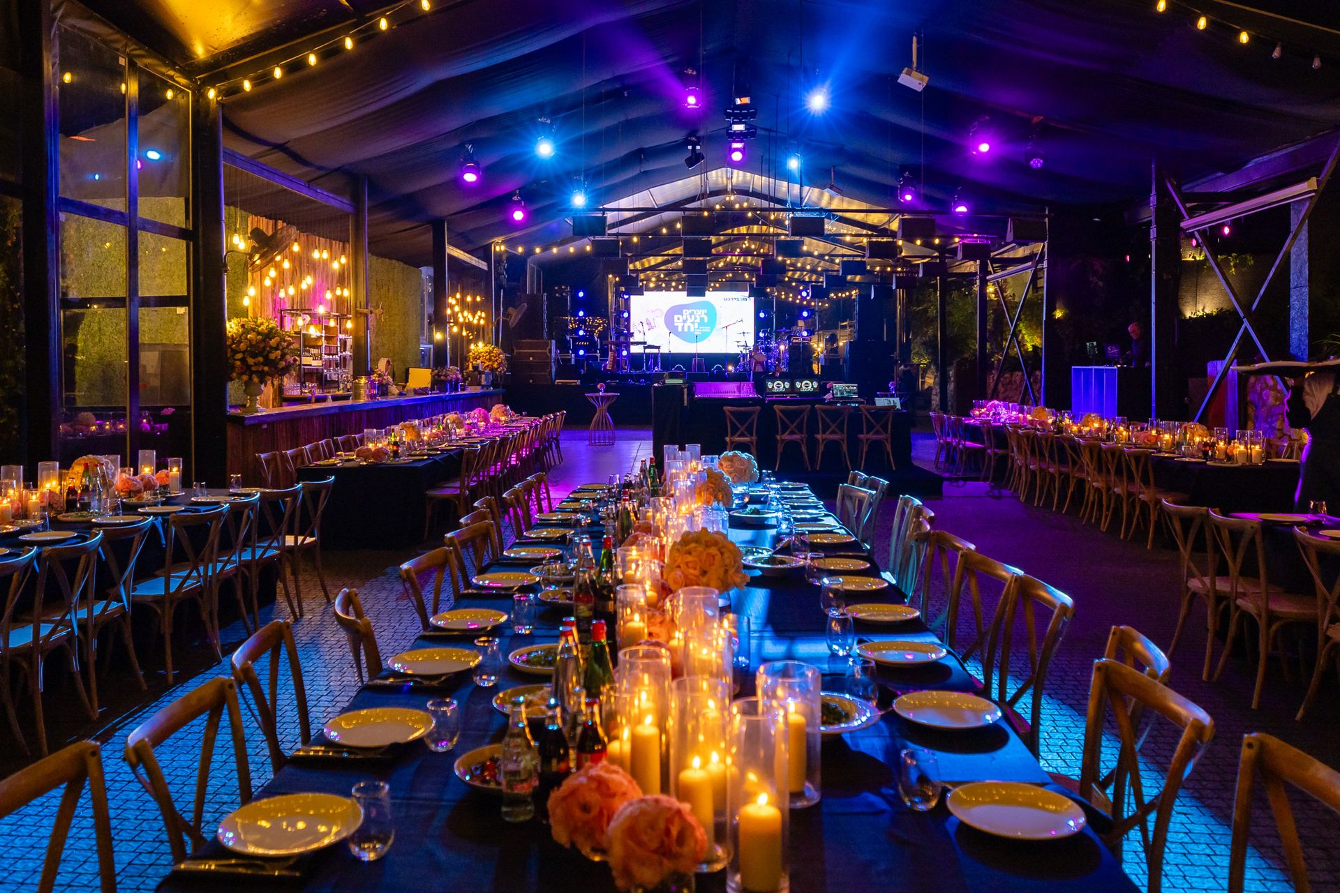 A candlelit event venue at night with long dinner tables, string lights, and a live band on stage, the kind of night people in Easton, Maryland buy tickets for.